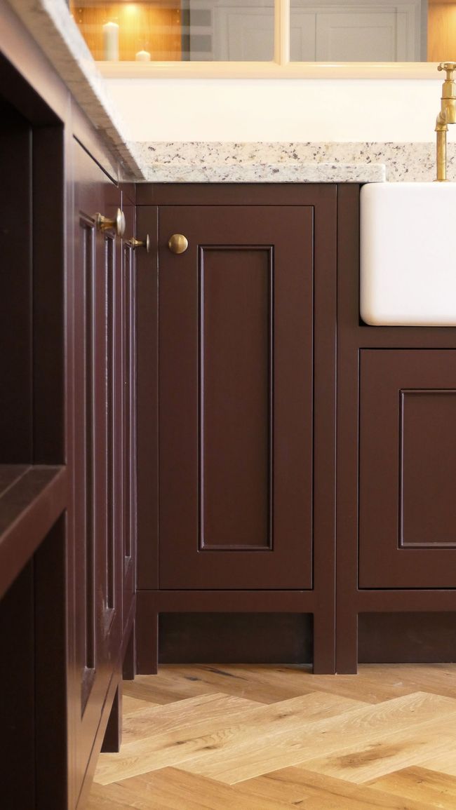 Deep burgundy Verona Shaker cabinetry with pencil beading, a brass knob and a butler sink