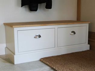 Cream storage bench with a wooden top and two drawers, each with metallic handles, placed against a light wall. Cozy, organized entryway setting.
