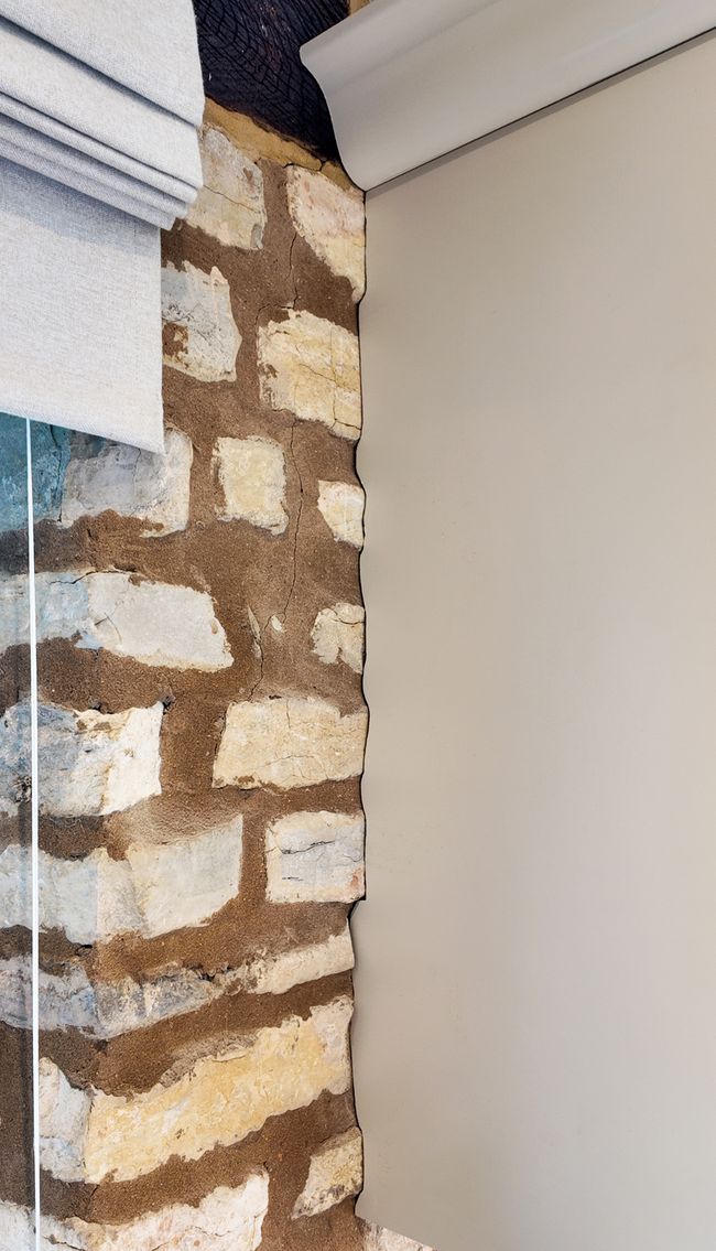 A close-up view of a textured wall featuring a mix of rough, exposed brick with a cabinet scribed against it.