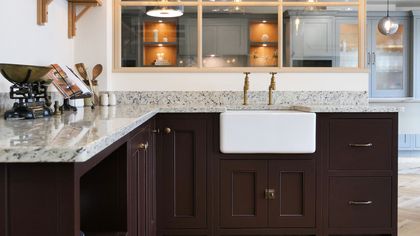Deep burgundy Shaker kitchen with a butler sink, brass taps and glass-fronted wall cabinets