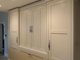 Cream-colored kitchen cabinets with silver handles fill the space. The cabinets have a sleek, shaker design, conveying a clean and organized atmosphere.