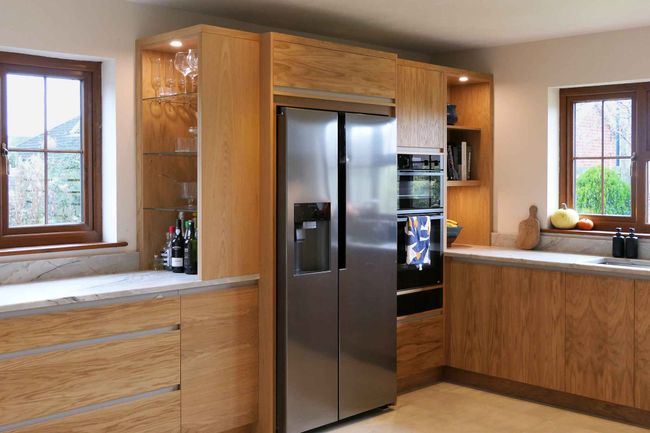 Oak Milan handleless kitchen with an integrated American-style fridge-freezer and a glass display cabinet