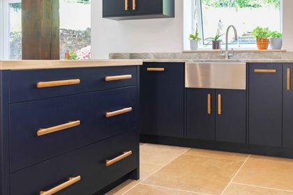 Hand-painted navy slab cabinetry with oak bar handles and a stainless farmhouse sink