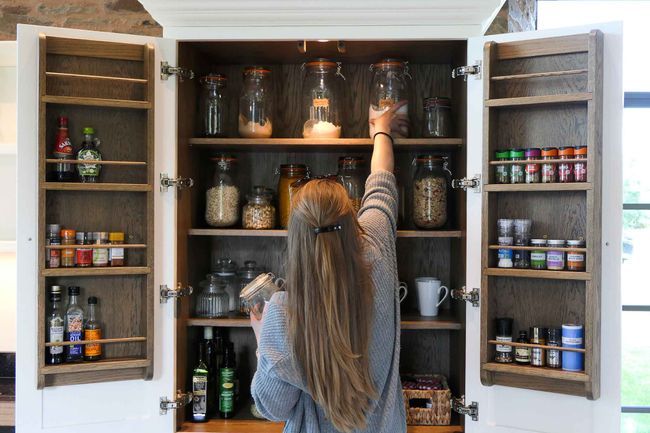 a handcrafted bespoke shaker kitchen featuring a beautiful larder cupboard painted in a soft white colour and crafted in dark walnut wood