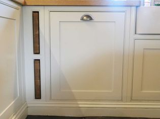 White kitchen cabinetry with a wooden countertop and metal pull handle. Vertical wine rack slots on the left add a touch of elegance. Clean and modern design.