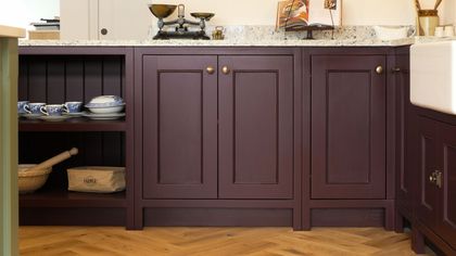 Deep burgundy Shaker base cabinets with brass knobs, open shelving and a granite worktop