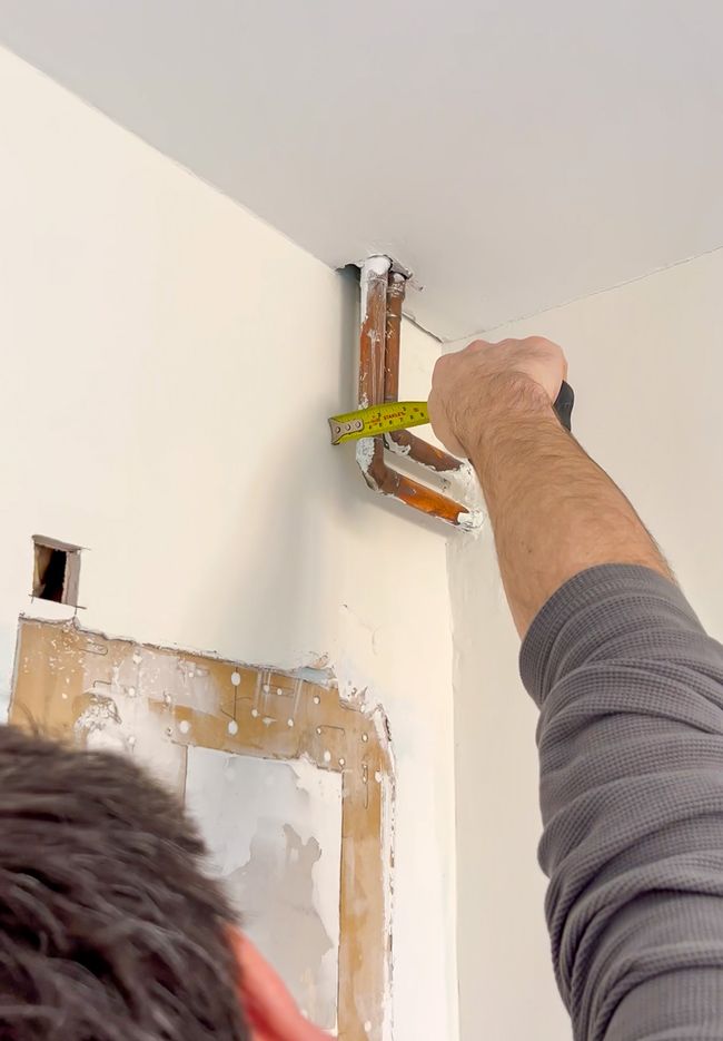 CAD technician measuring pipes in the corner