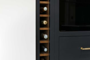 A vertical wine rack built into dark cabinetry is shown, holding several bottles on wooden shelves. A closed cabinet with a gold handle is beside it.