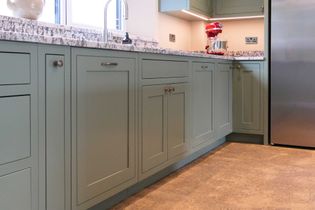 Shaker kitchen with green cabinets, a granite worktop, and stainless steel appliances. A red mixer adds a pop of color on the counter.