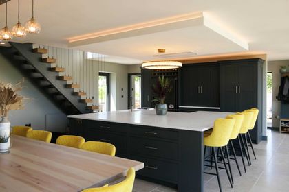 Bespoke dark navy kitchen island with integrated ovens and brass bar handles, made to fit the space