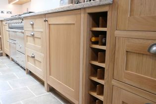 Shaker kitchen with oak cabinets, drawers with silver handles, a built-in wine rack, and granite countertops, on a tiled floor.