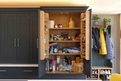 Fitted dark navy larder and boot room with a stocked pantry, coat hooks and shoe storage