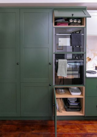Dark green shaker cabinetry with double oven, storage cupboards above and below