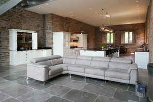 Grey sofa in the foreground with the bright white cabinetry behind, set in a stone wall room.
