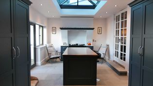 A shaker kitchen with navy blue cabinets and a central island under a skylight. Light streams in, creating a bright, inviting atmosphere with minimal decor.