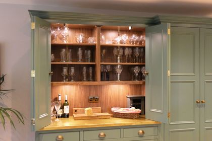 Counter-top cupboard with bi-fold doors open, storing glassware with worktop space