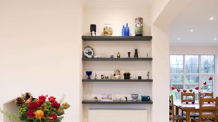 An interior features wall shelves with colourful ceramics. A dining area is visible, adorned with heart decorations. .