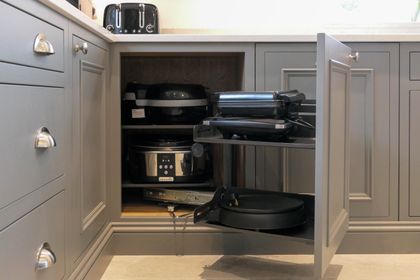 Pull-out corner carousel storing pots and pans in grey Shaker cabinetry