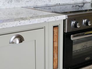 Shaker kitchen with white speckled granite countertop, grey cabinets, and a stainless steel oven with black glass door, conveying a sleek, clean feel.