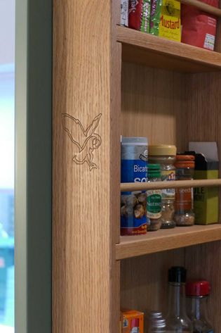 Wooden spice rack stocked with spices and condiments, features a carved owl on the frame.