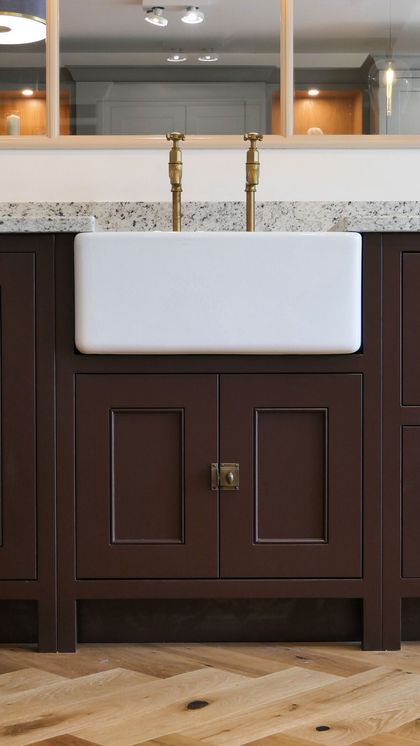 White butler sink set into rigid deep burgundy Shaker cabinetry with a granite worktop