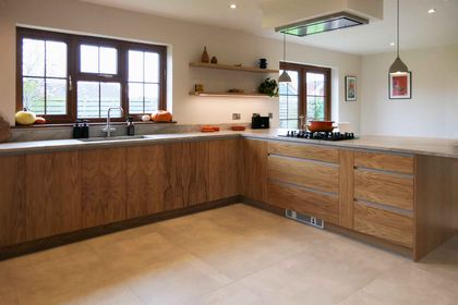 Fitted oak handleless kitchen run with marble worktops, a gas hob and windows above the sink