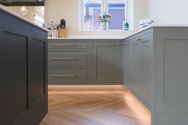 Sage green Shaker kitchen with warm under-cabinet LED lighting