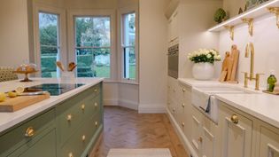 Kitchen with light-coloured cabinetry and a wooden floor, featuring a rug and windows providing natural light.