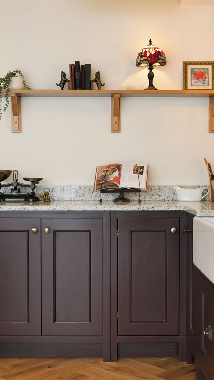 Fitted deep burgundy Shaker kitchen run with a granite worktop, brass taps and a butler sink