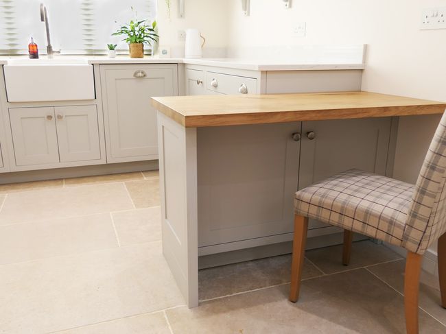 Shaker kitchen with a cream AGA stove, grey cabinetry, and sleek countertops. The atmosphere is clean and minimalist, accented by metal handles.