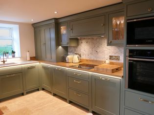 Shaker kitchen with sage green cabinets and wood countertops. Features a stove, toaster, kettle, and double oven.