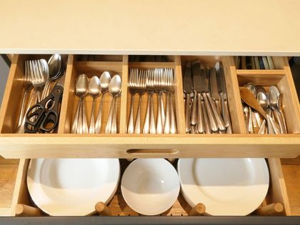 Hidden drawer below a cutlery drawer, holding plates in a handmade kitchen
