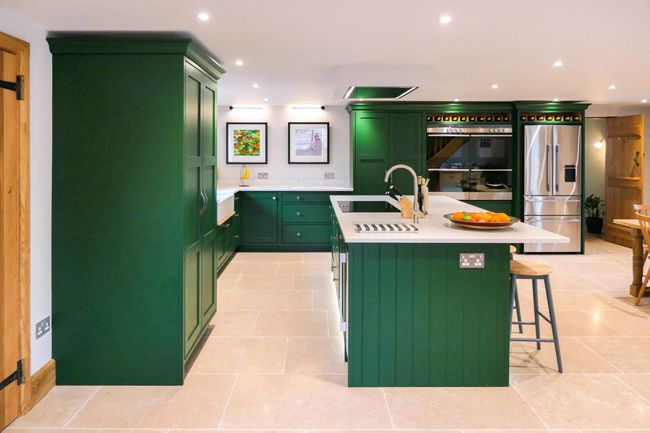 Shaker kitchen with a sleek island, featuring a wooden knife block and olive oil bottle. Bright spotlights light up the space.