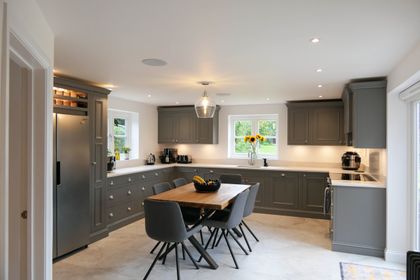 Full view of a grey Shaker kitchen with an oak dining table and an American-style fridge-freezer