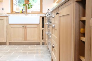 Bright shaker kitchen with oak cabinets, granite countertops, and farmhouse style sink. Modern appliances and wine storage create a warm, functional space.